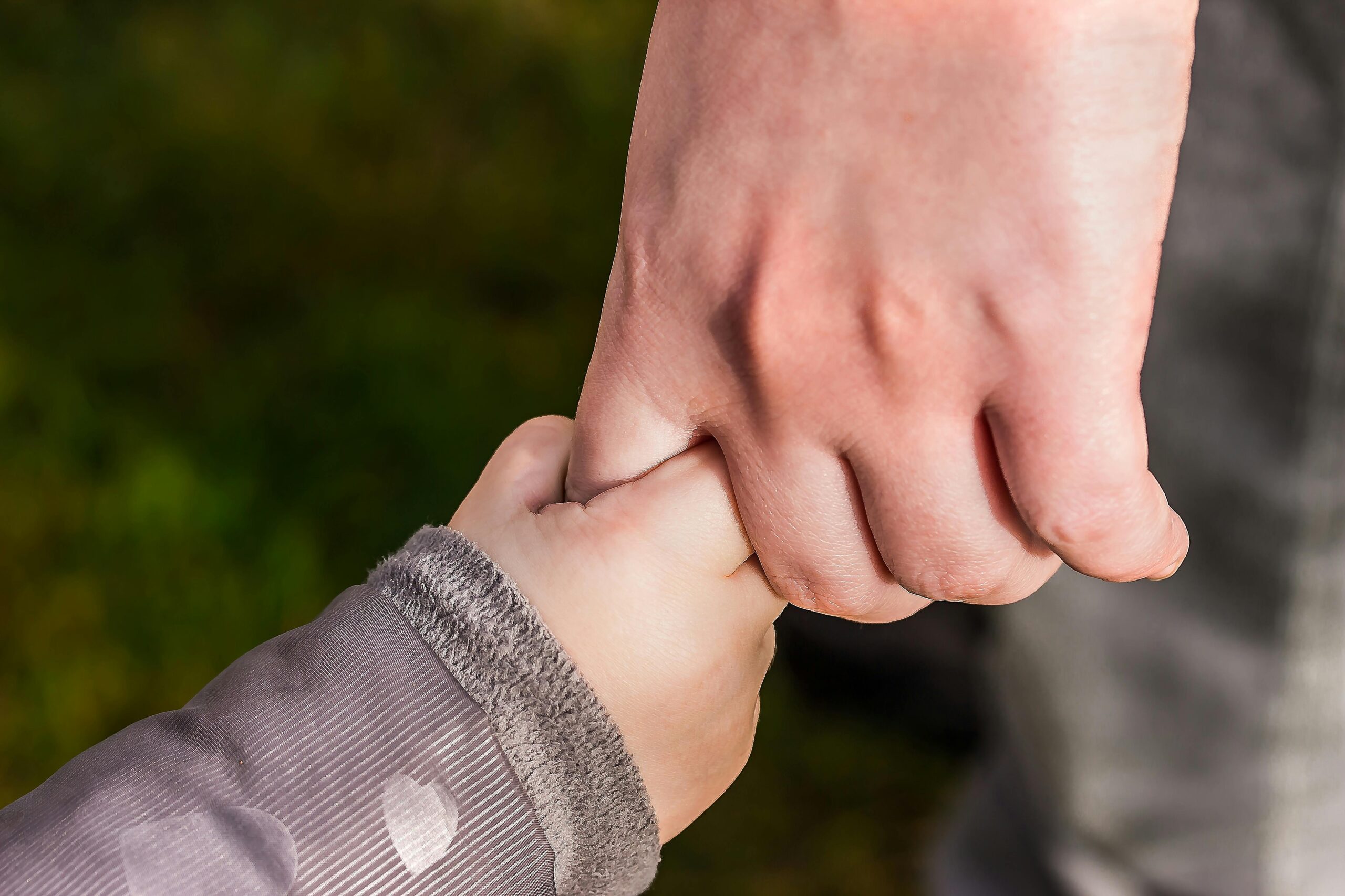 Child holding parent’s hand, representing attachment-based therapy, emotional safety, and connection in trauma-informed Christian parenting.