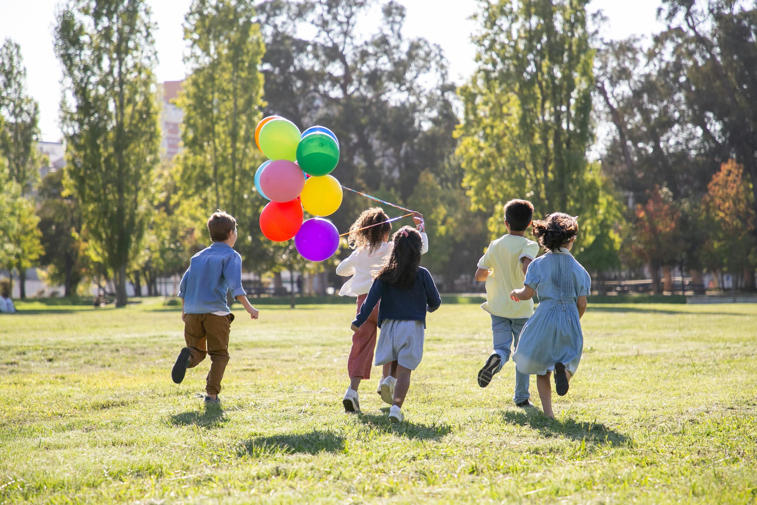 Children running with balloons, symbolizing emotional health, joyful connection, and healing for adoptive families through attachment-based parenting.