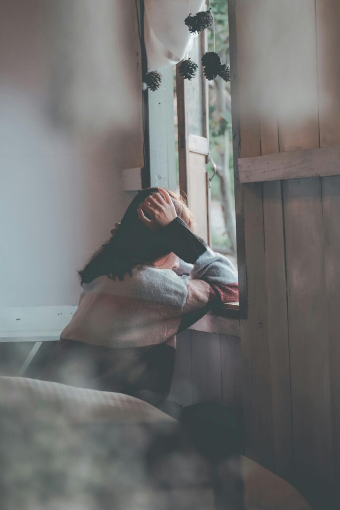 Overwhelmed woman holding her head in her hands, symbolizing the emotional weight of parenting through trauma, identity shifts, and spiritual exhaustion.